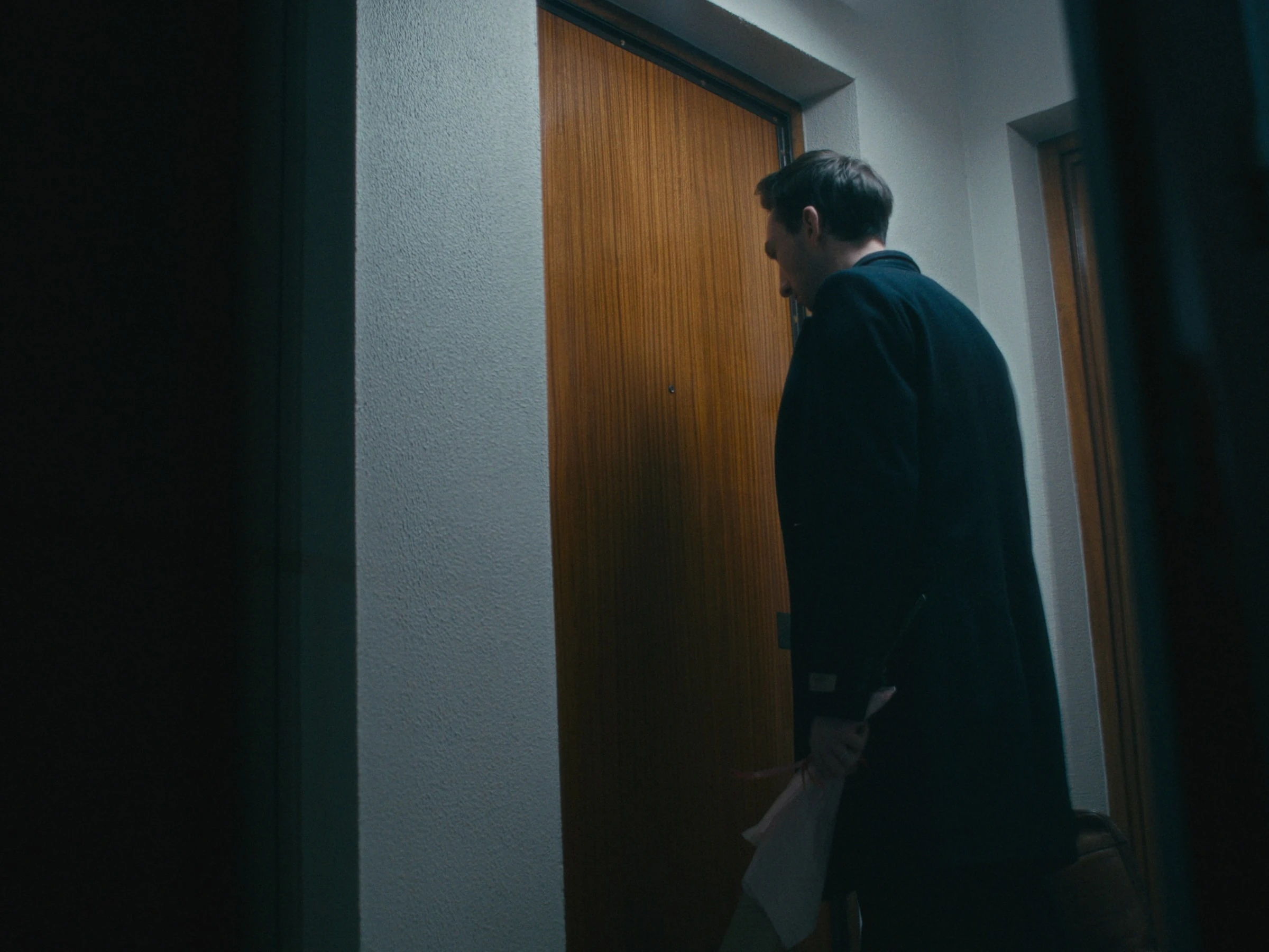Photogramme du film — couloir en clair-obscur, silhouette dans l'embrasure.