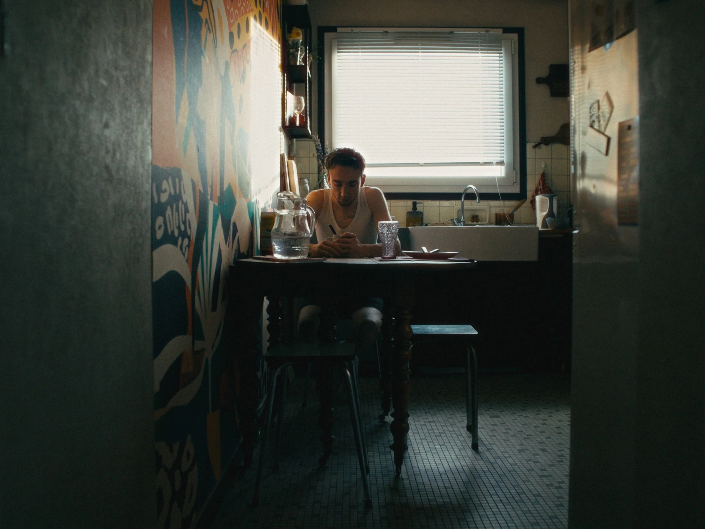 Photogramme du film — intérieur graffé, tons teal-vert.